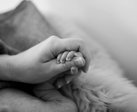 Manos de adulto sosteniendo las manos de un recién nacido